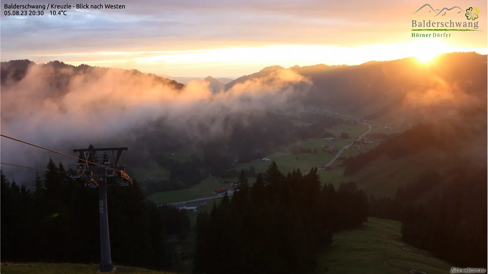 Sommerabend: Tief hängende Wolken ziehen über die Waldhänge, die untergehende Sonne färbt sie orange
