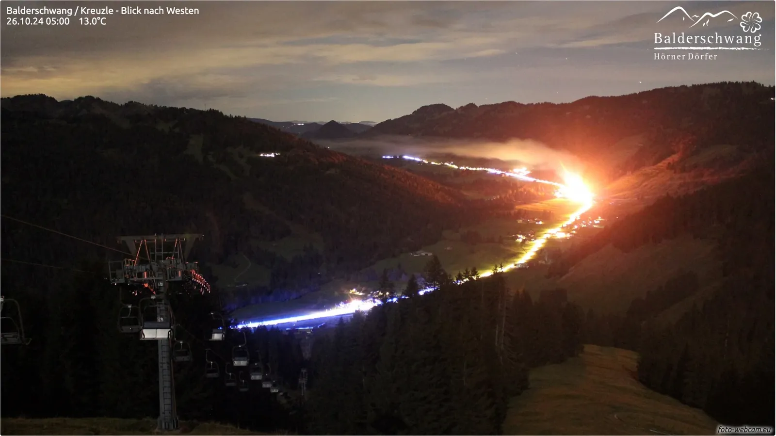 Nachtaufnahme vom 26. Oktober 2024: Im Tal leuchtet der Brand im Mitarbeiterhaus eines Hotels hell orange, auf der Straße blaue Lichtspuren