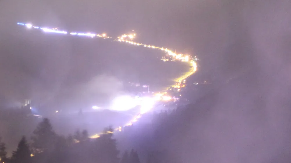 Webcam-Blick bei Nacht: dichter, hell angestrahlter Rauch liegt über dem ganzen Talboden, an einer Stelle grelle Scheinwerfer